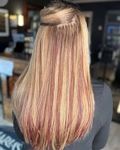 Back view of long blonde keratin fusion extensions with vivid red and pink highlights