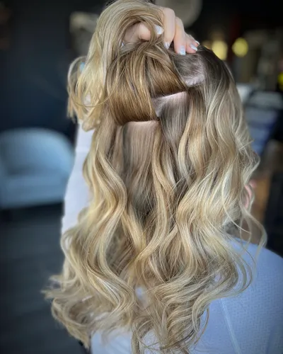 Hand-parting hair to reveal a seamless weft extension track during installation