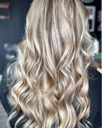 Dimensional blonde highlights with long, voluminous waves — back view